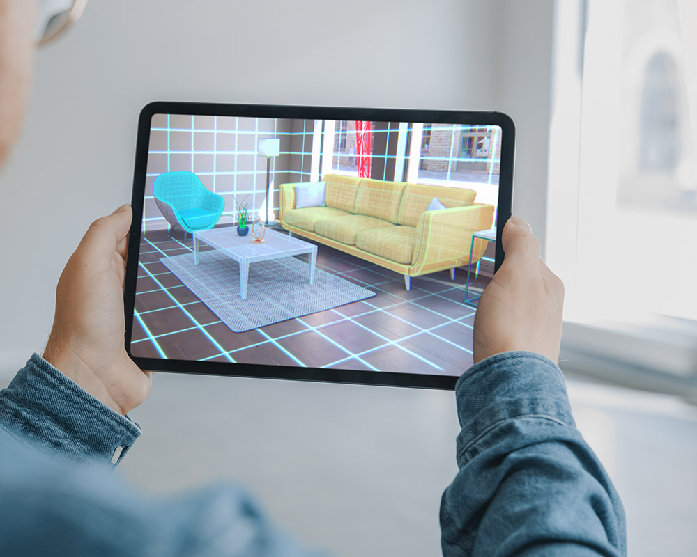 Decorating Apartment: Man Holding Digital Tablet with AR Interior Design Software Chooses 3D Furniture for Home. Man is Choosing Sofa, Table for Living Room. Over Shoulder Screen Shot with 3D Render